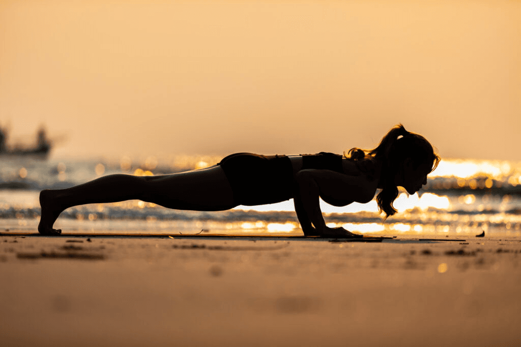 A woman holding plank on the beach during sunset